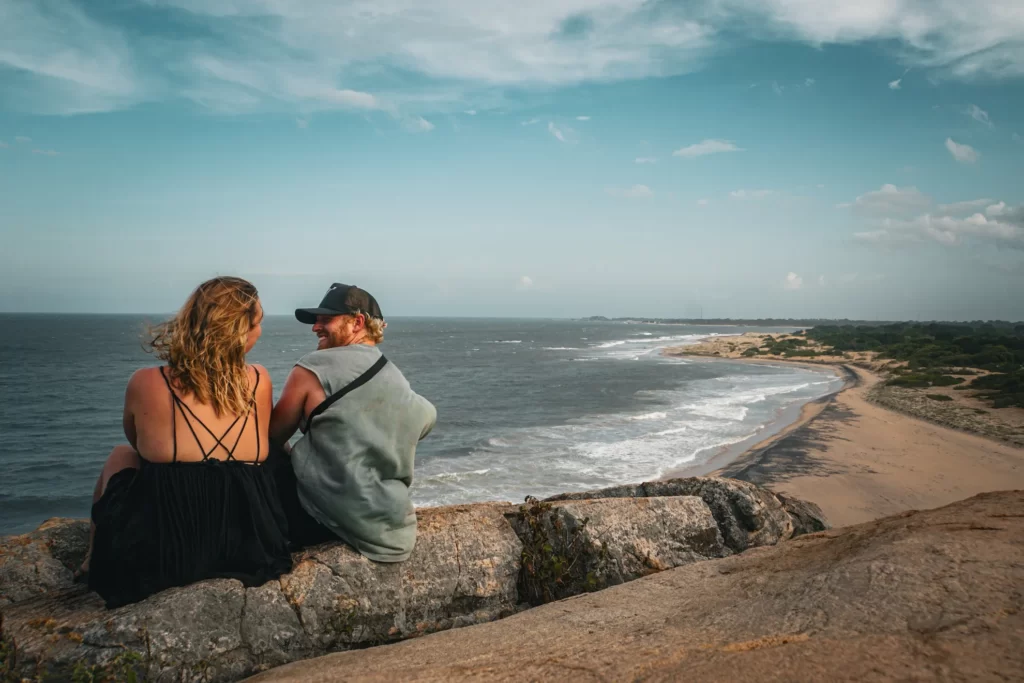 A smiling couple sitting on Elephant Rock looking over the coastline