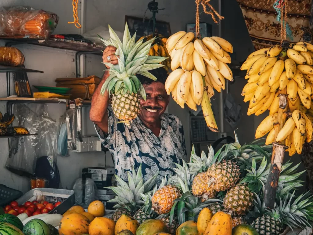 A local man holds up a pineapple to sell in a small fruit store in Arugam Bay