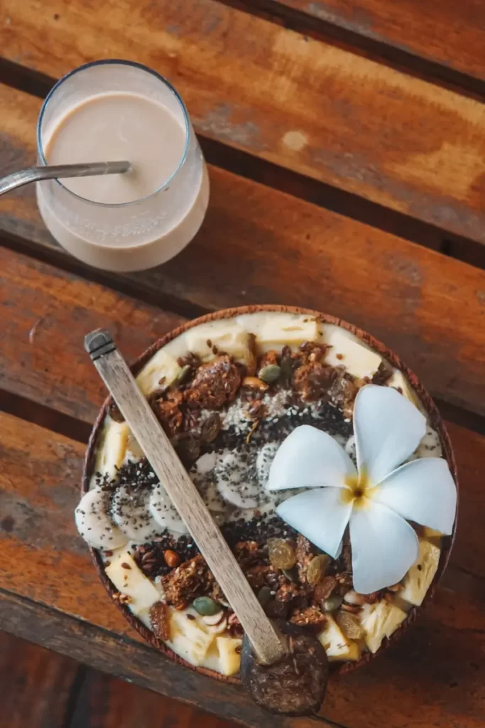 A banana and coconut smoothies bowl and an ice coffee which is given as the free breakfast at Oasis Bay