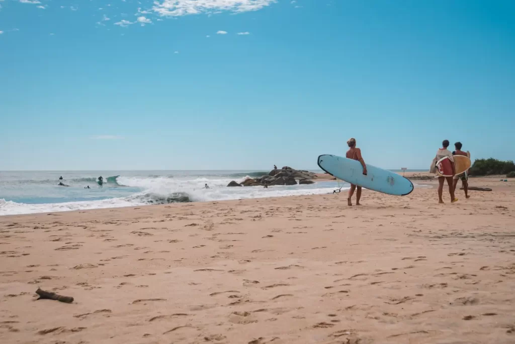 A group of people from a surfboard camp carrying their boards to the break