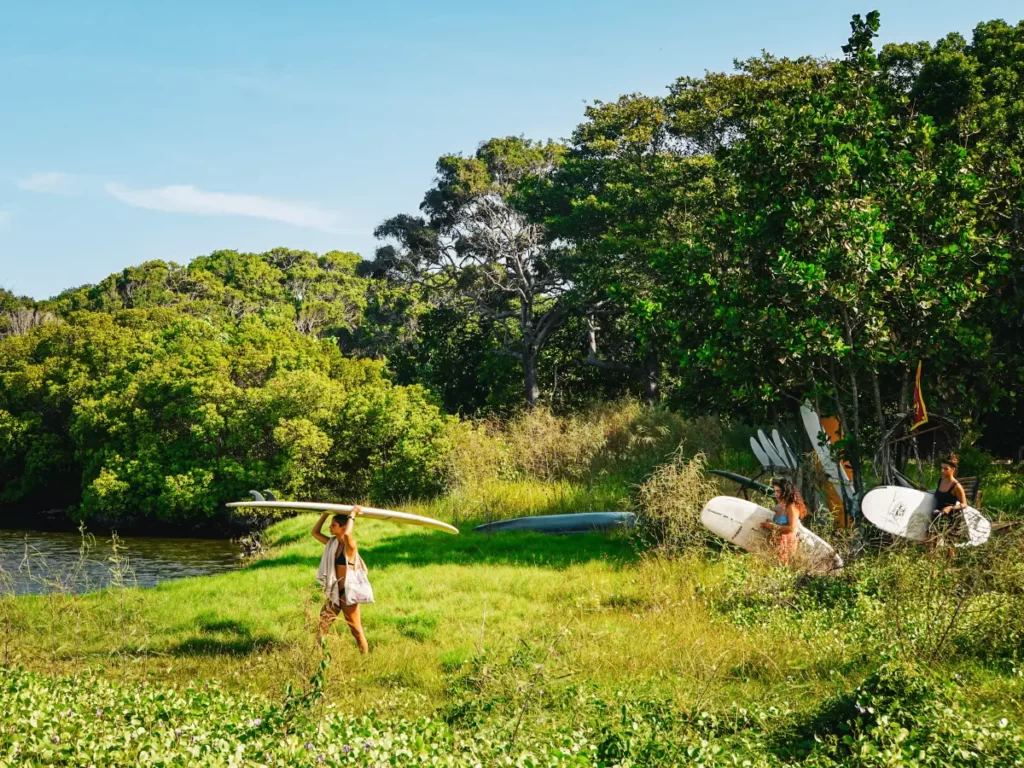 A group of girls carry surfboards through the tanks in Arugam Bay