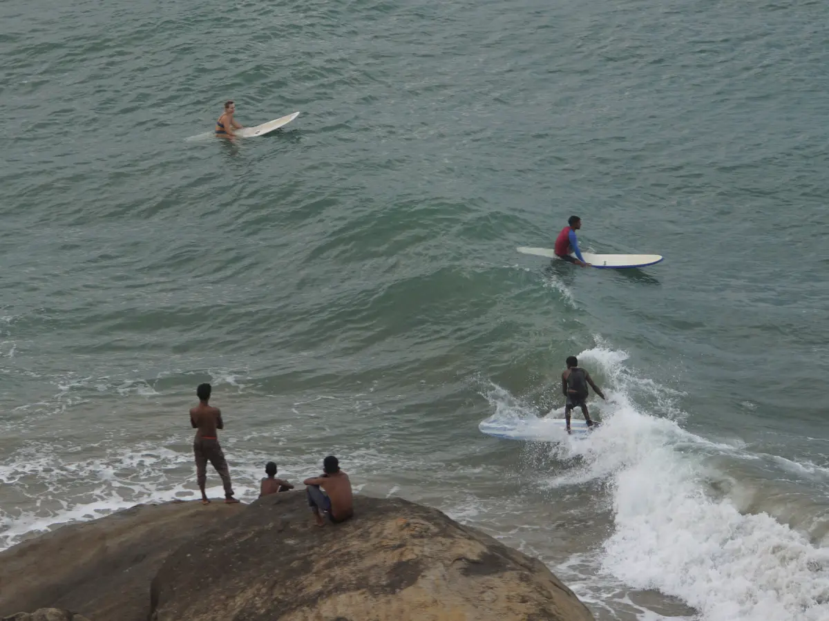 Local boys watch a longboard surfer on a wave at Elephant Rock Beach Arugam Bay