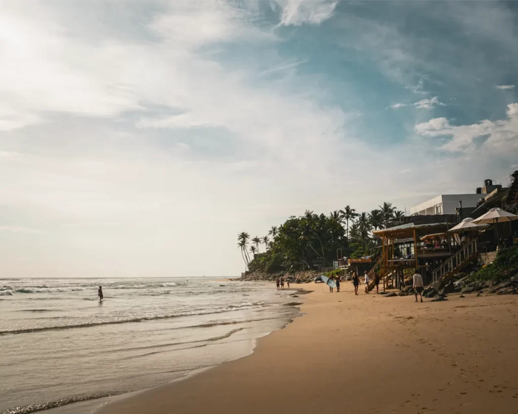 People walking down Ahangama Beach at dusk