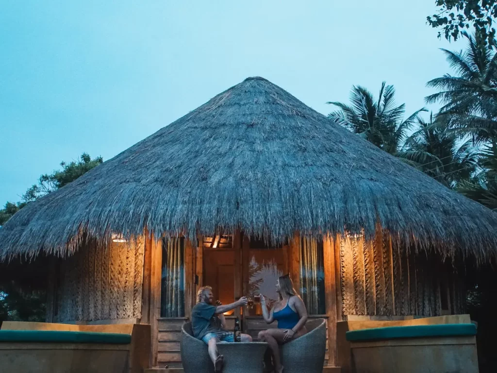 A couple sits outside the back of their cabanas at Jetwing Surf have a few drinks