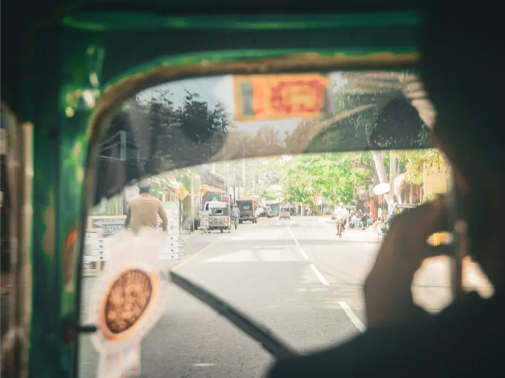 A Tuk Tuk driver on the phone looking through the window at Arugam Bay