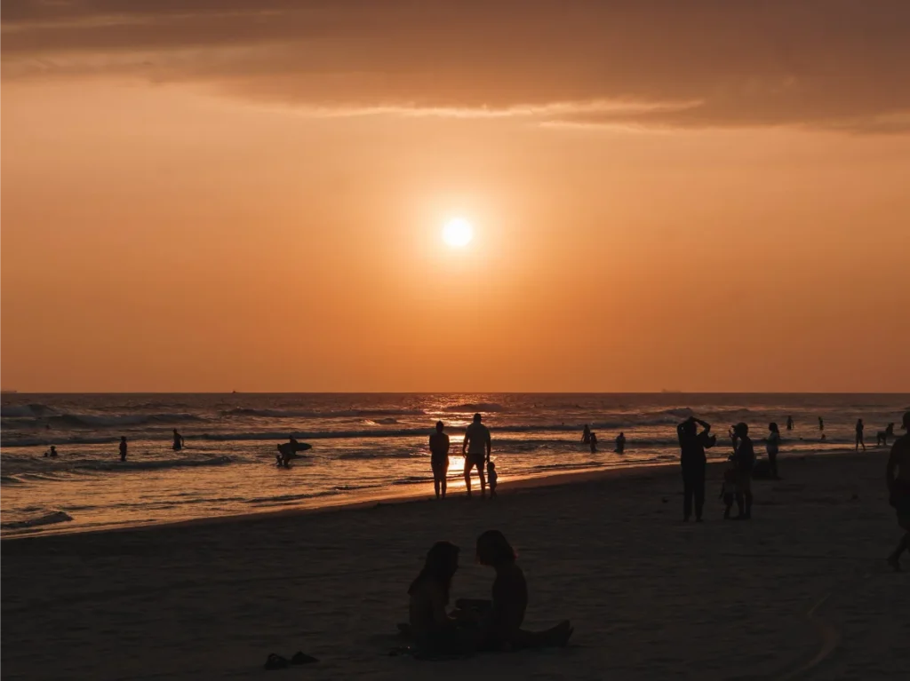 a bright orange sky and people hanging out at Kabalana Beach at sunset