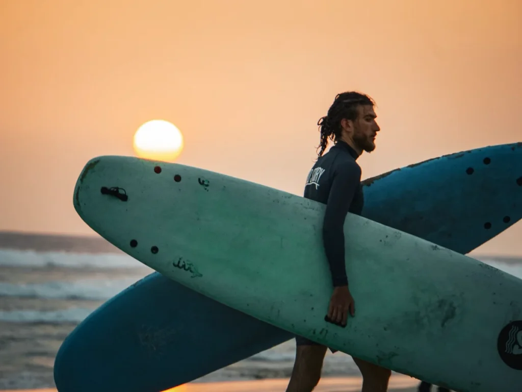 A beginner carrying surfboards at Kabalana Beach