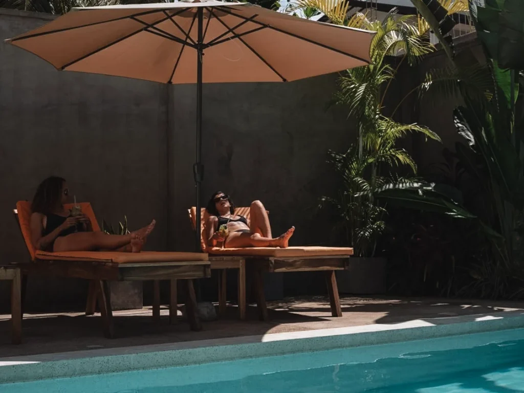 Two girls drink cocktails near the pool at Lum Residence