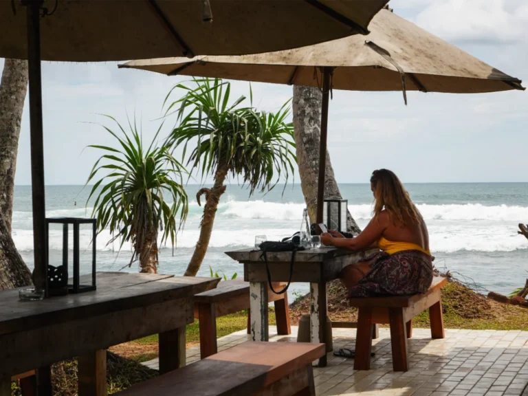 A girl sits on the tables watching the surfers at Swell Shacks in Madiha