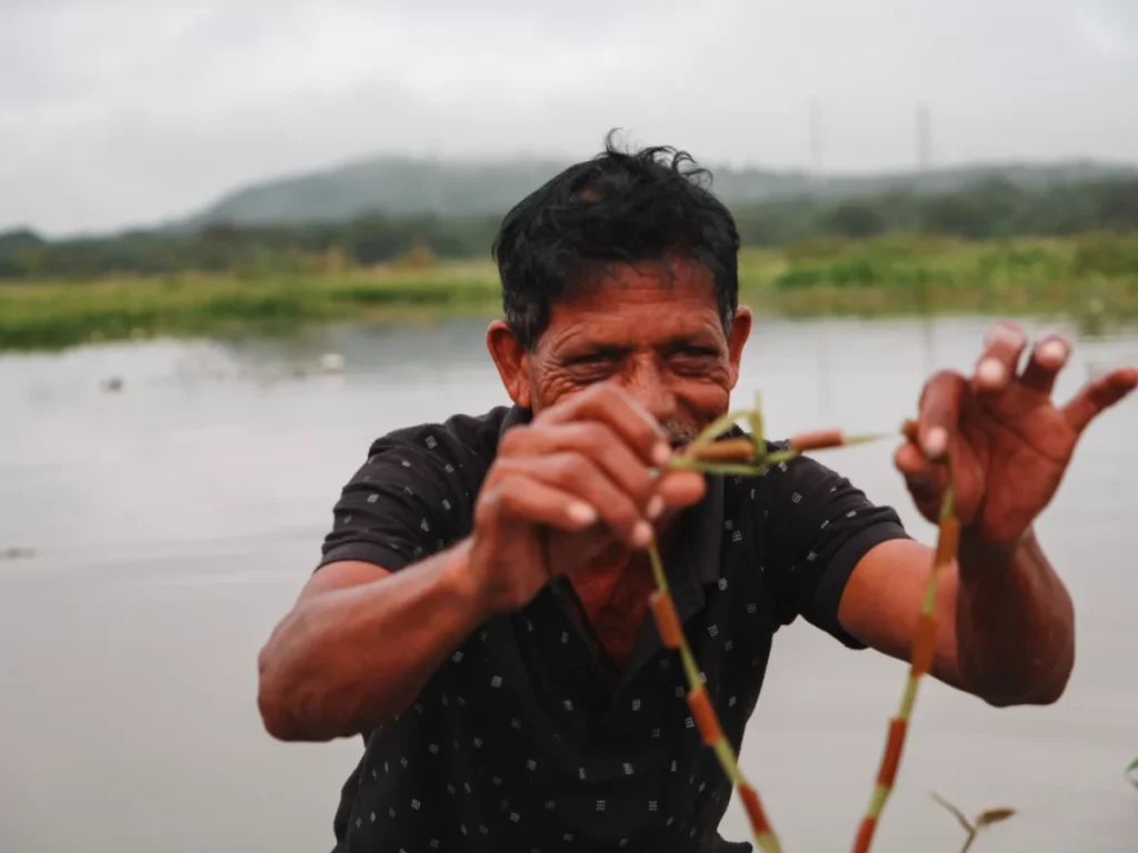 A local man makes a reed necklace on a boat ride at Habarana lake