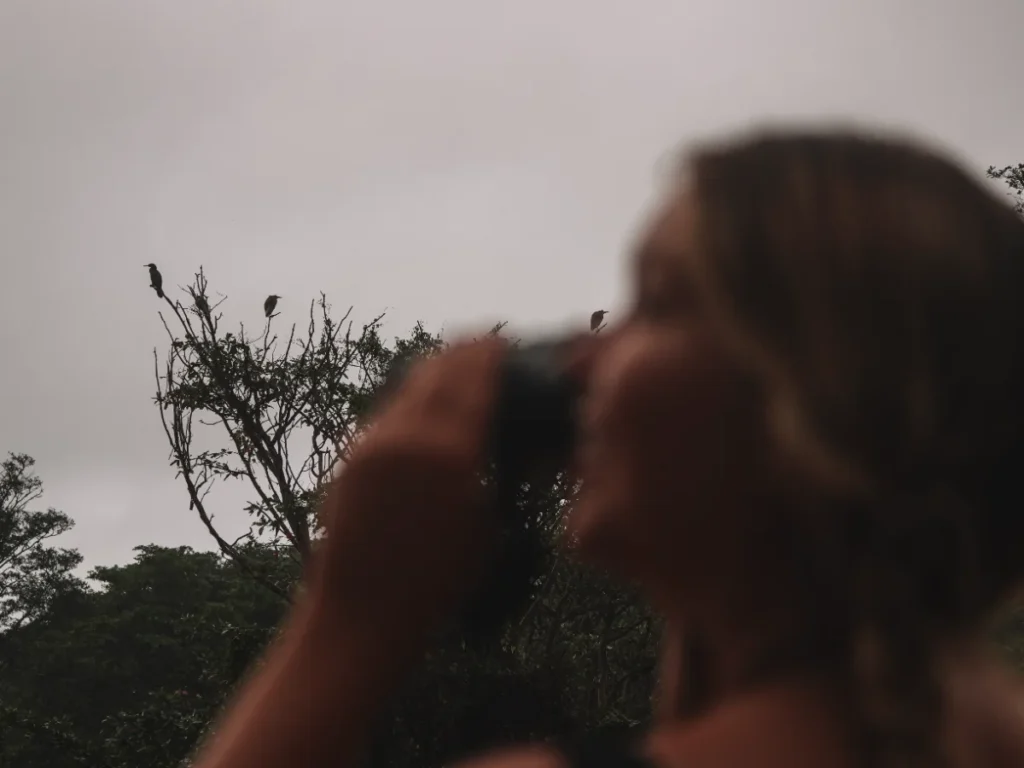 A girl spots birds with binoculars at a local tank near Sigiriya 